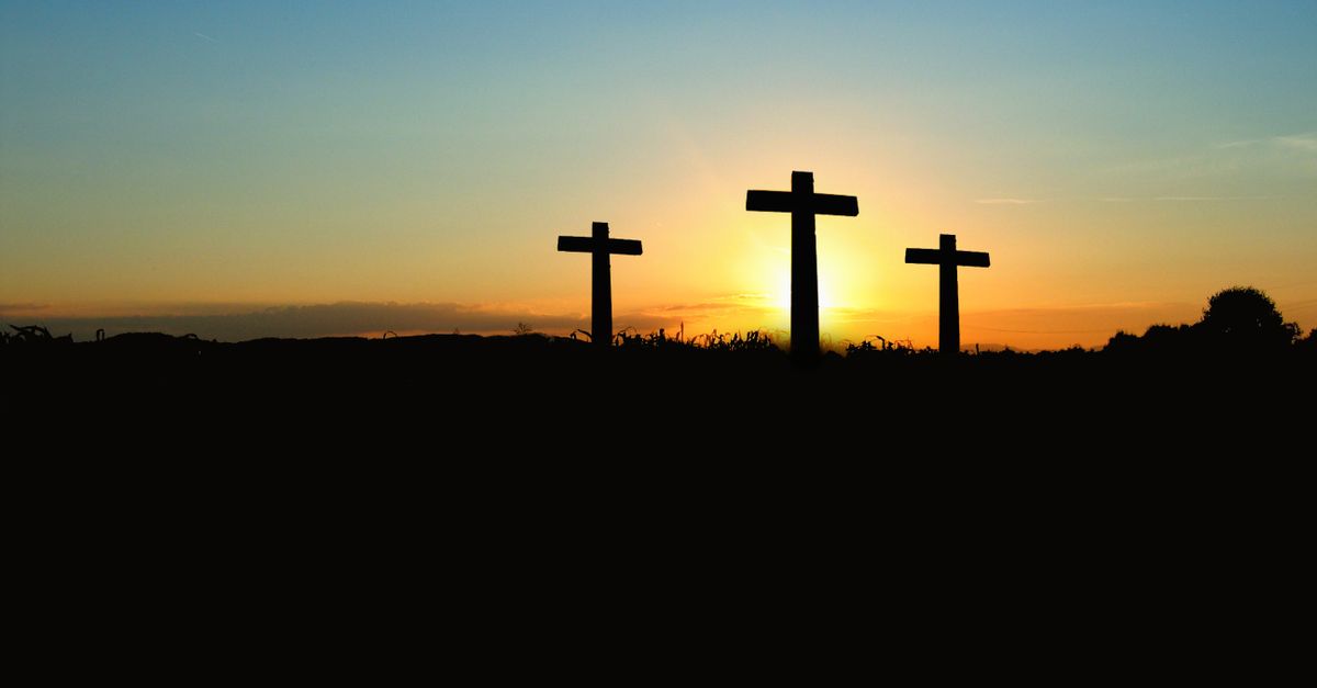 Silhouette of three crosses against a vibrant sunset sky.