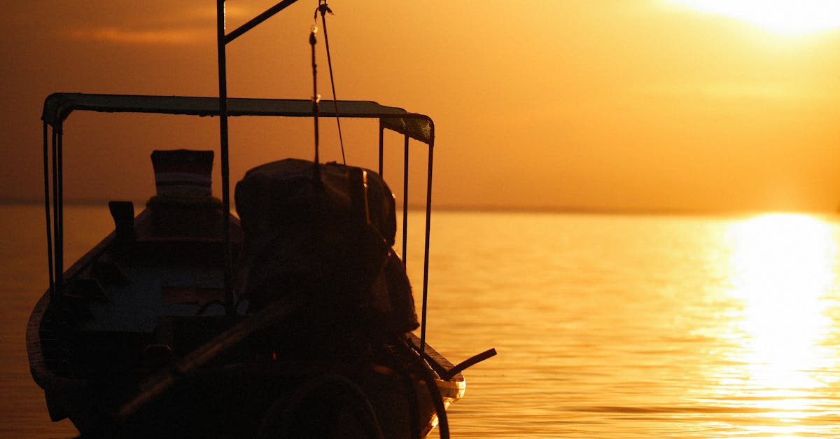 Peaceful silhouette of a boat against a golden sunset shining over tranquil sea waters.