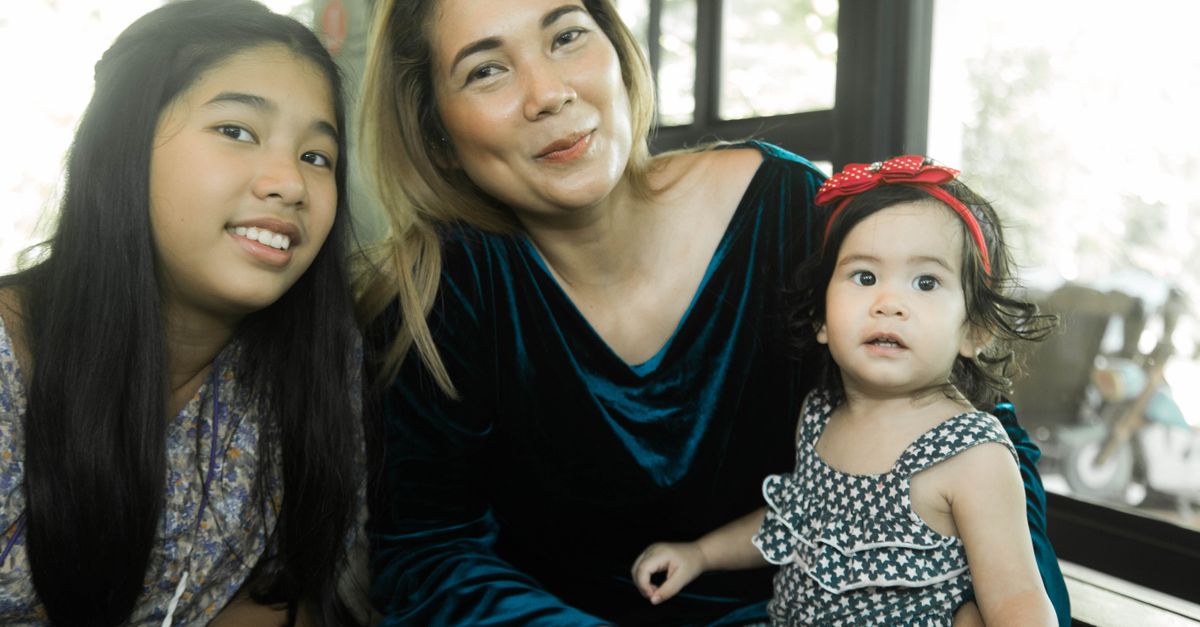 A joyful portrait of a mother with her two daughters, showcasing a moment of togetherness and happiness indoors.