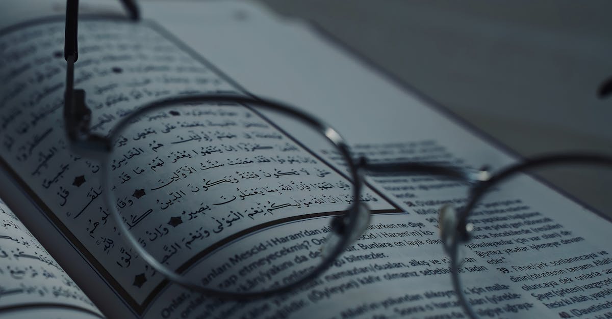 Close-up of eyeglasses on a book with Arabic script, symbolizing knowledge and learning.