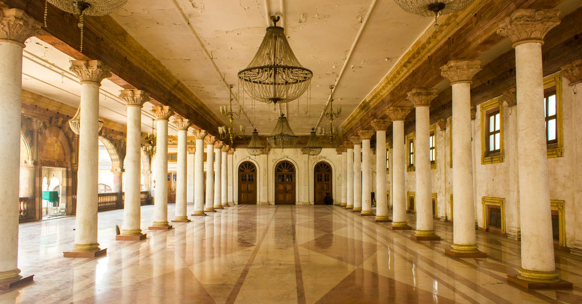 Spacious hall with columns and chandeliers in Rajwada Palace, a historic site in Indore, India.