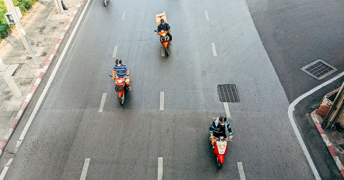 High angle view of motorcyclists riding on a city road, showcasing urban transportation.