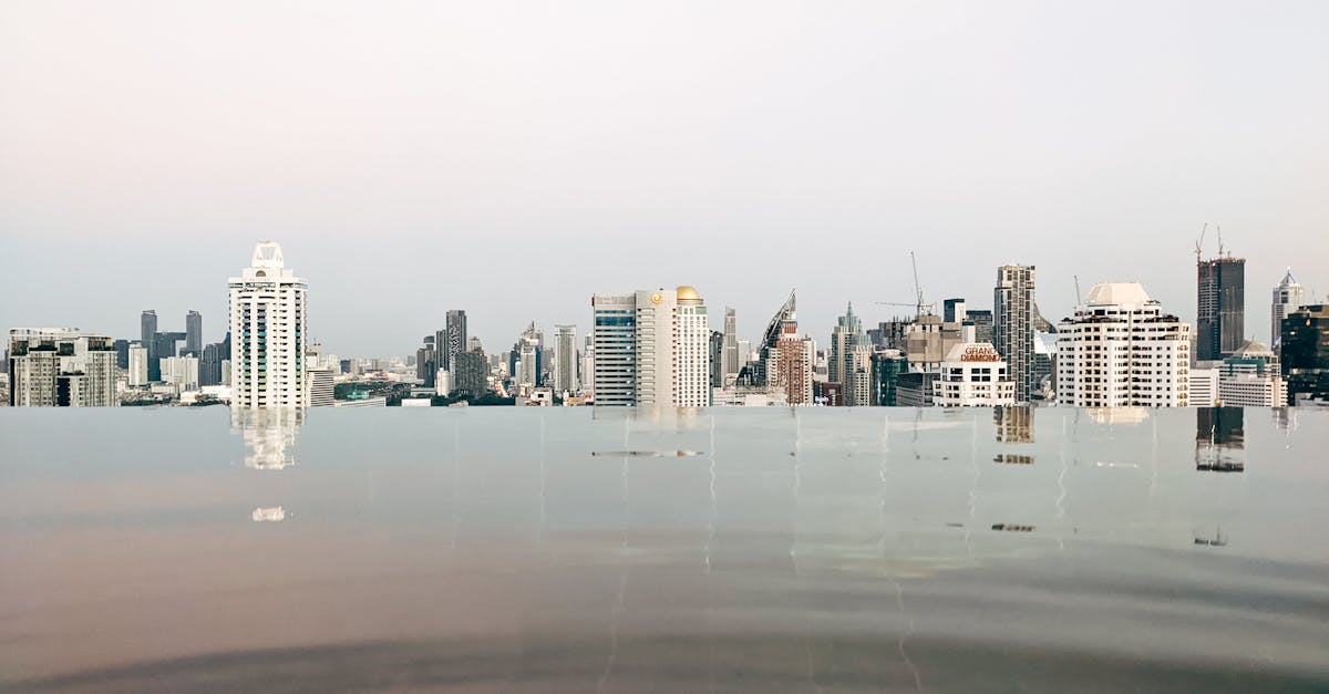 Tranquil infinity pool with reflections of the Bangkok skyline under a calm sky.
