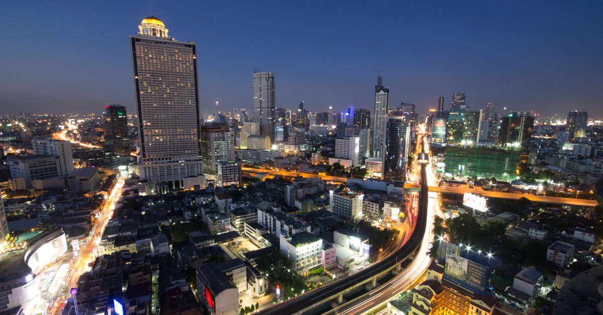 A breathtaking aerial view of a vibrant cityscape at night, showcasing illuminated skyscrapers and bustling roads.