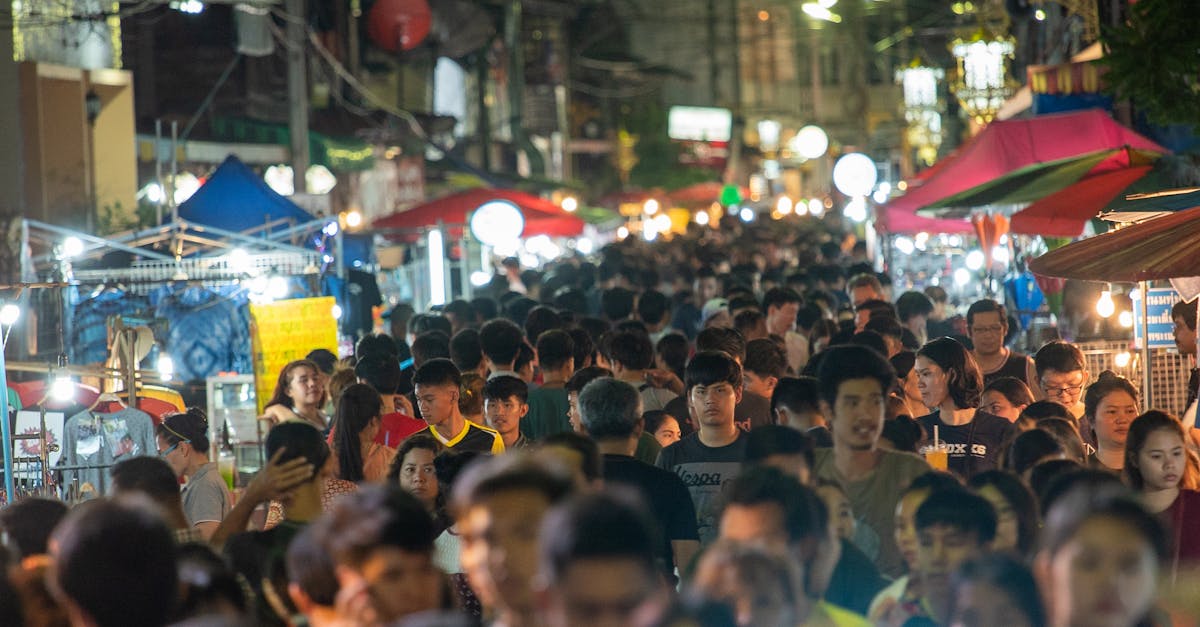 Lively night market scene with a crowded street filled with people and vibrant stalls.