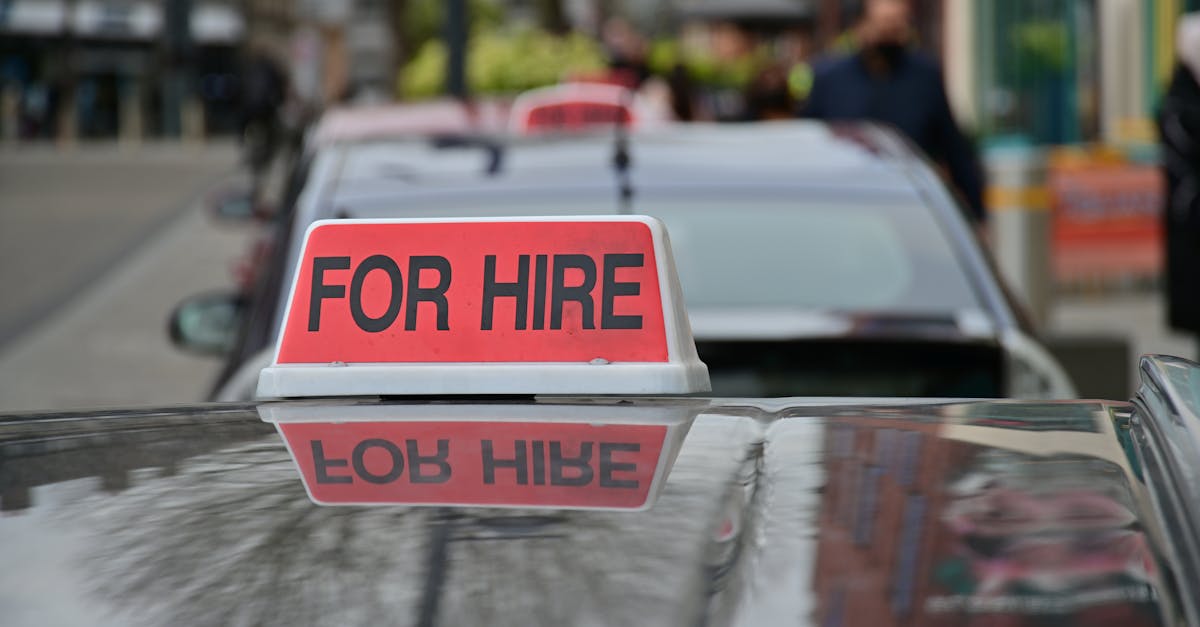 Close-up of a red 'For Hire' sign on a taxi, reflecting the urban street.