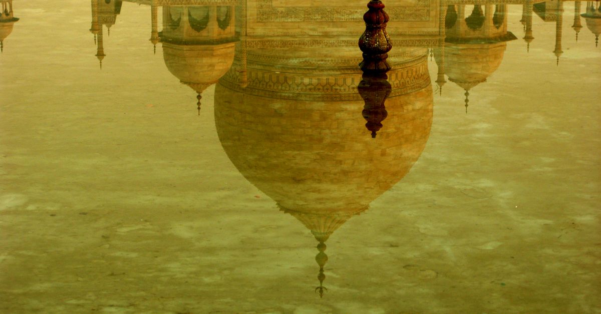Stunning reflection of the Taj Mahal's dome in tranquil water, showcasing architectural grandeur.