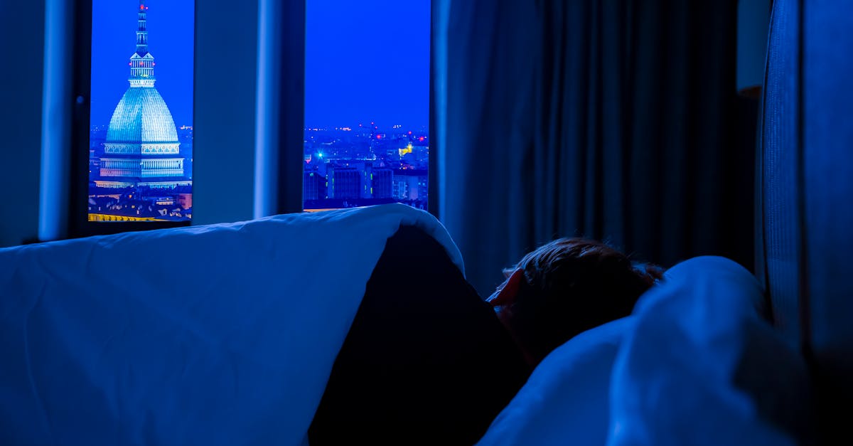 A serene view of Turin's night skyline featuring Mole Antonelliana, seen from a cozy bedroom.