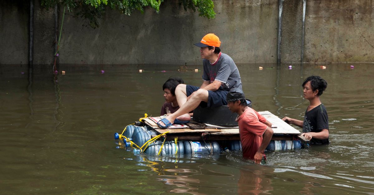 Men maneuvering a makeshift raft through floodwaters in Jakarta, showcasing resilience.