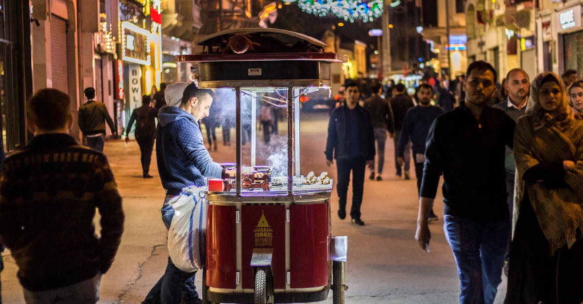 A bustling night market scene with a street vendor selling food under bright lights.