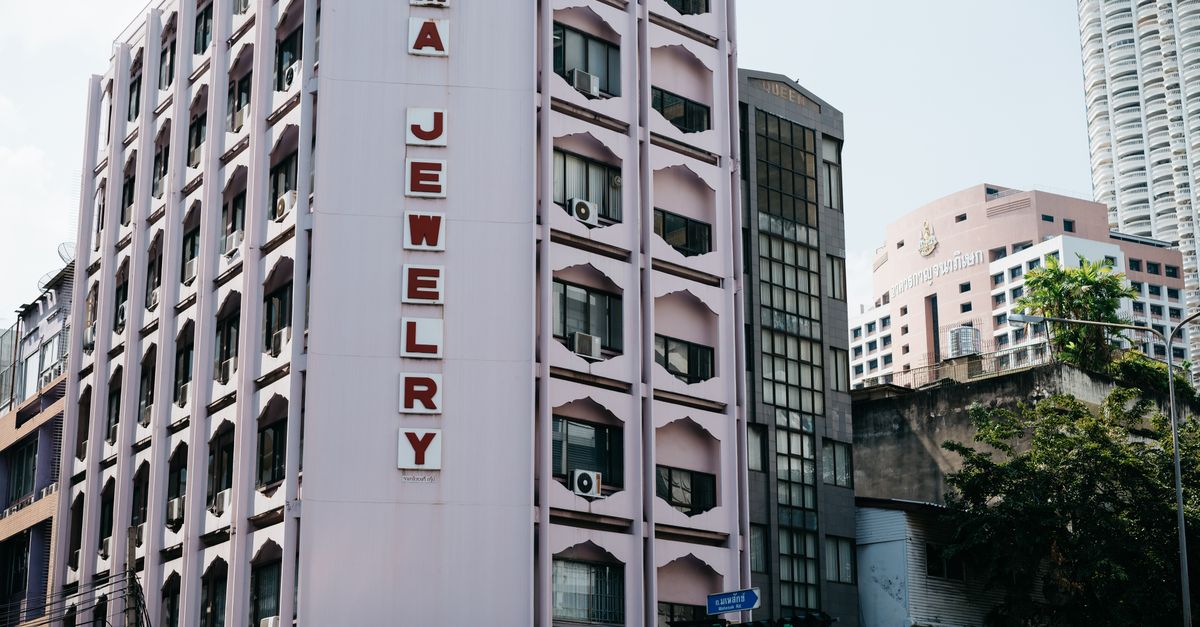 A vertical urban building facade with 'RAMA JEWELRY' sign in Bangkok, Thailand.