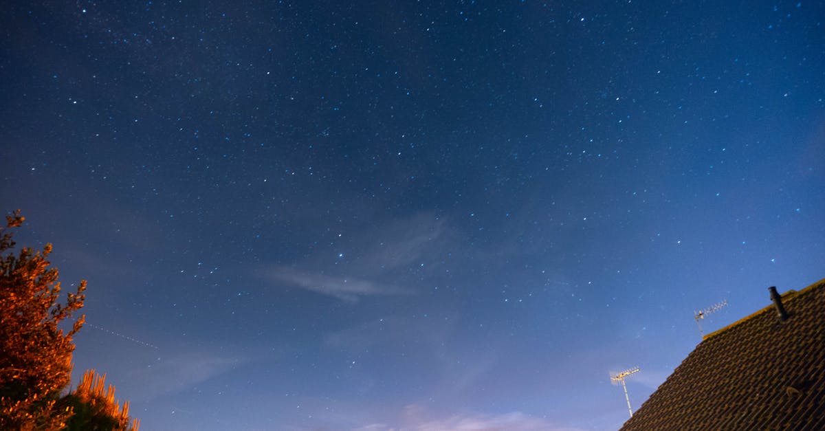 A star-filled night sky over suburban rooftops and trees, capturing celestial beauty.