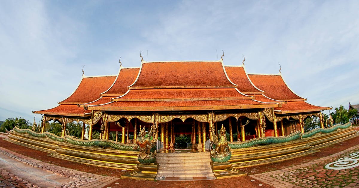 Stunning Buddhist temple with red roof and gold accents in a serene park setting.