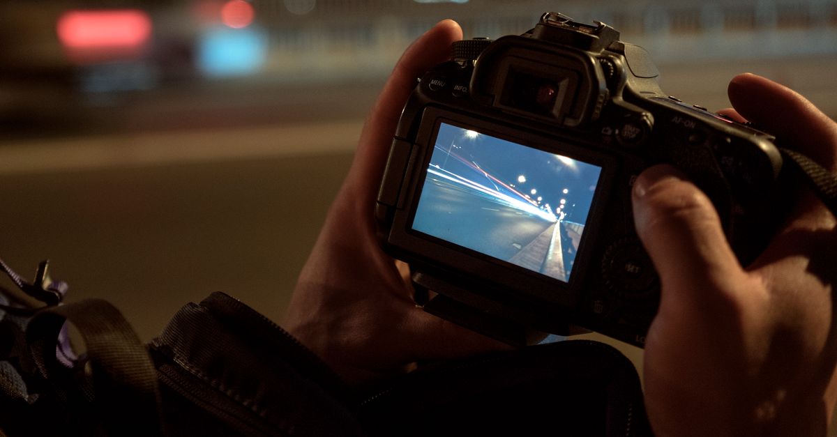 Close-up of a camera screen showing a long exposure photo taken at night with bokeh lights in the background.