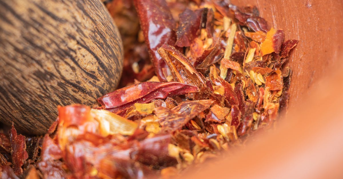 Close-up of crushed red chili peppers in a mortar, showcasing spicy ingredients.