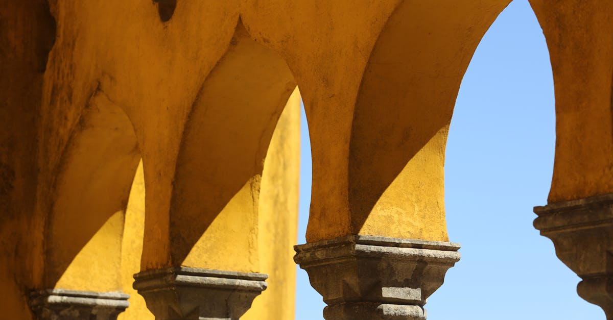 Close-up of historic yellow stone arches under a vibrant blue sky, showcasing architectural beauty.