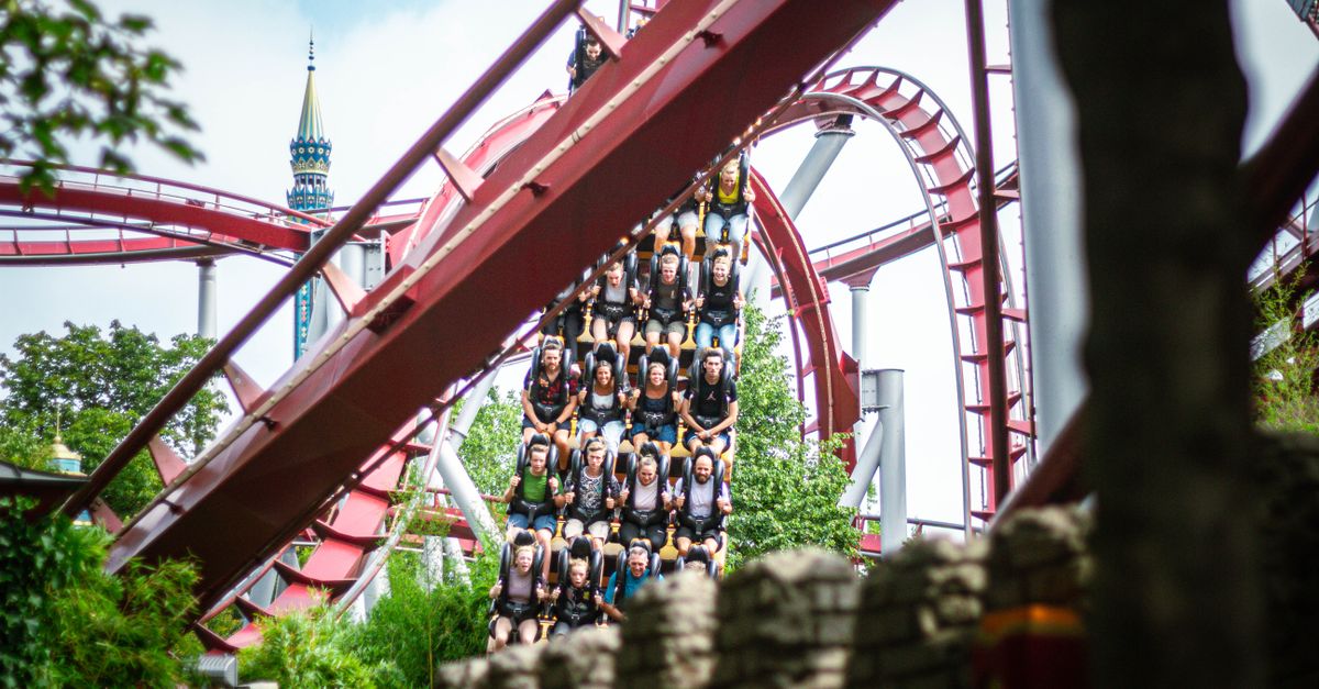 Experience the thrill of a roller coaster ride at a bustling amusement park during daytime.