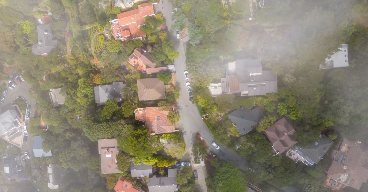 Aerial view of a suburban neighborhood with mist partially covering the houses and roads.