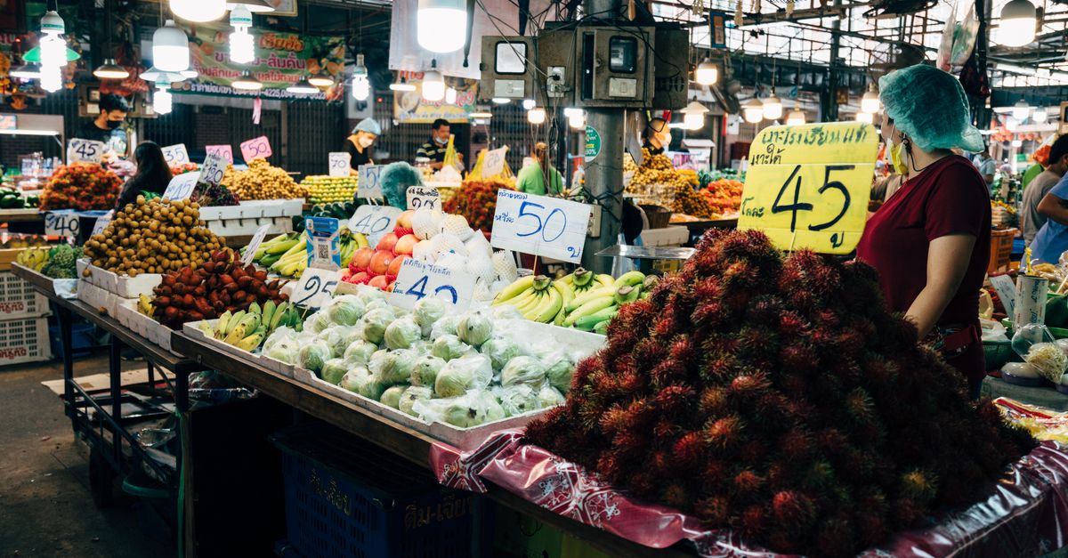 Colorful market stall with exotic fruits and vendors in a bustling Southeast Asian bazaar.