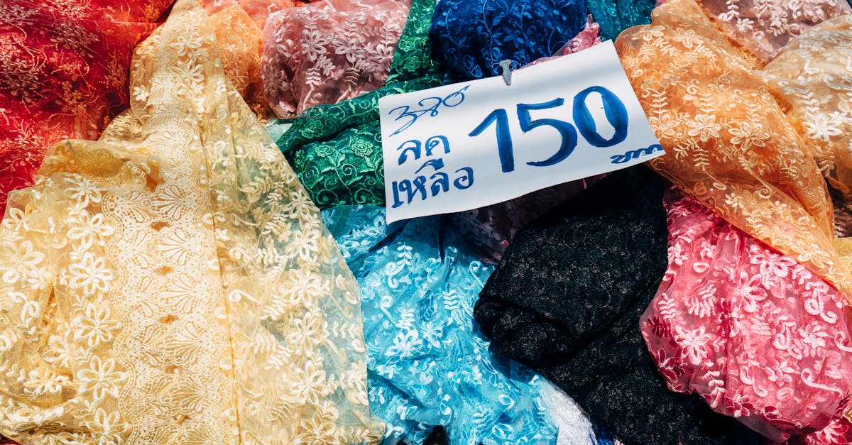 A vivid assortment of lace fabric displayed with a discounted price tag in a market setting.