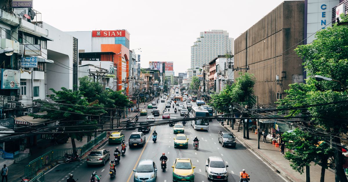 Traffic and bustling activity on a busy street in Bangkok, Thailand. Cars and motorcycles dominate the scene.