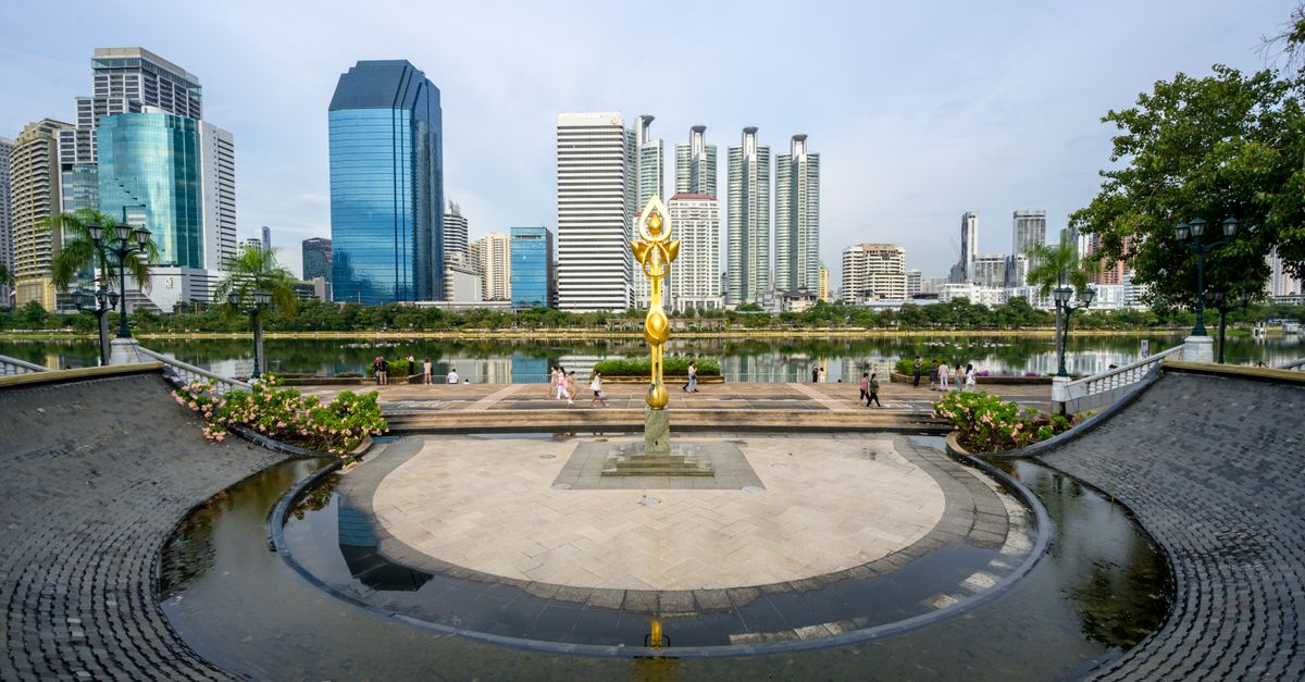Stunning view of a modern city skyline with a golden monument in a park.
