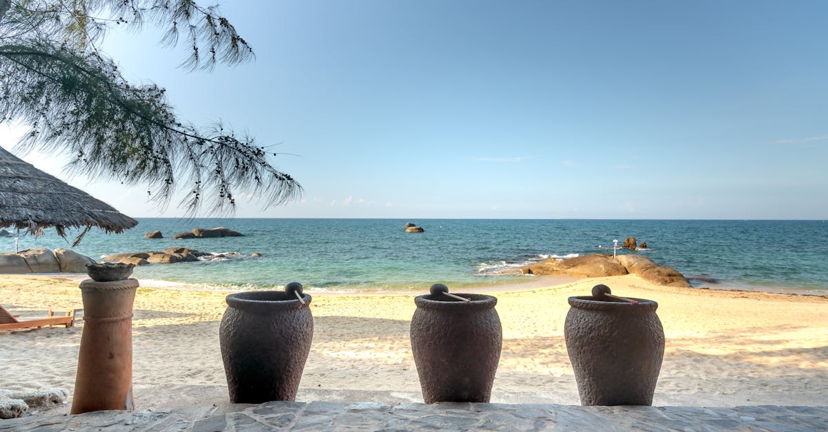 Tranquil beach scene featuring clay pots, sand, and ocean under a bright summer sky.