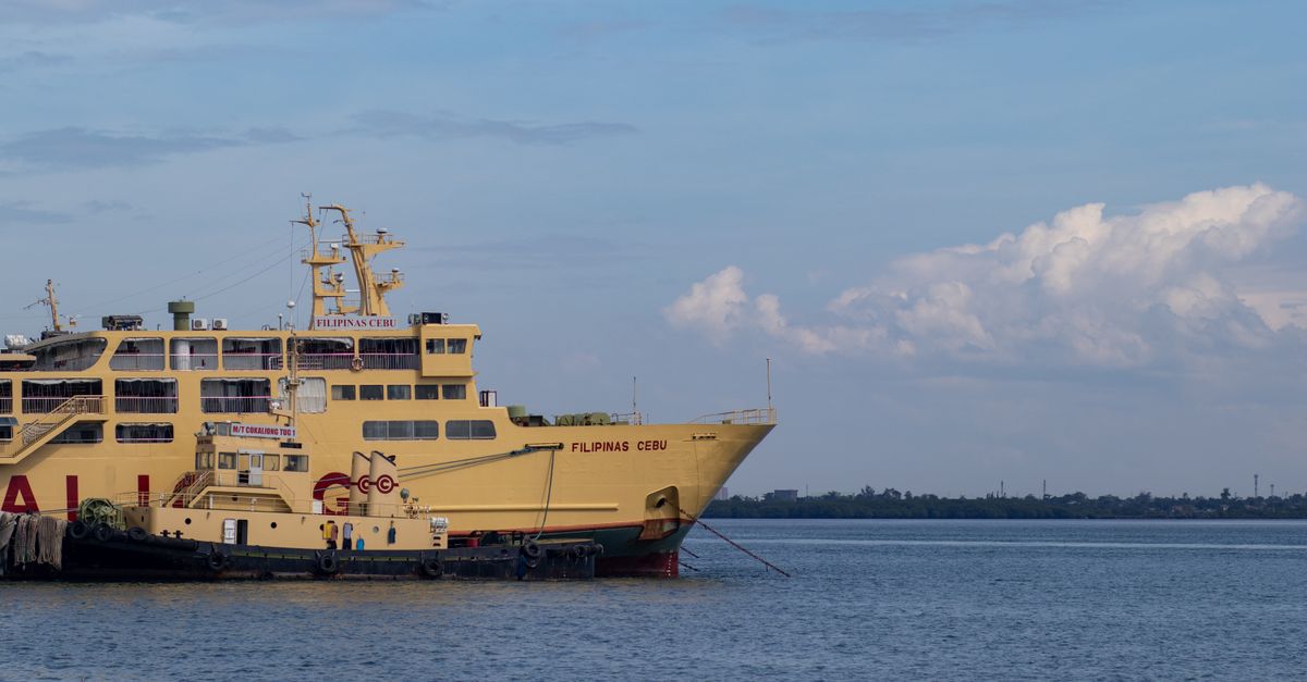 A large yellow ferry named 'FILIPINAS CEBU' docked in calm ocean waters under a clear sky.