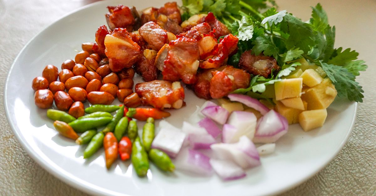 Vibrant Asian appetizer on a plate featuring fresh vegetables, nuts, and marinated meat.
