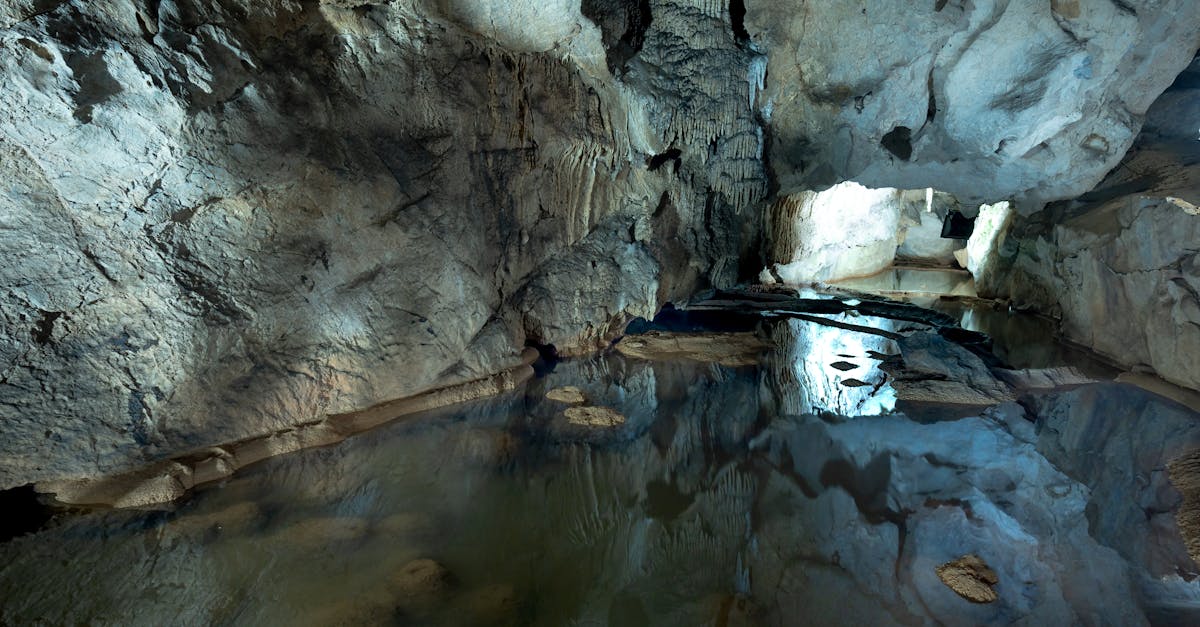 Explore the serene ambiance of a natural cave featuring stunning rock formations and reflective pools.