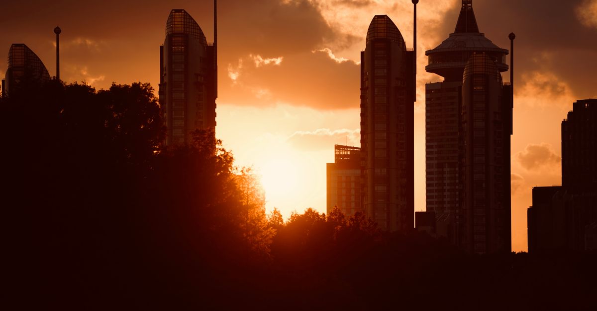 Silhouetted skyscrapers set against a vibrant sunset, depicting modern cityscape.