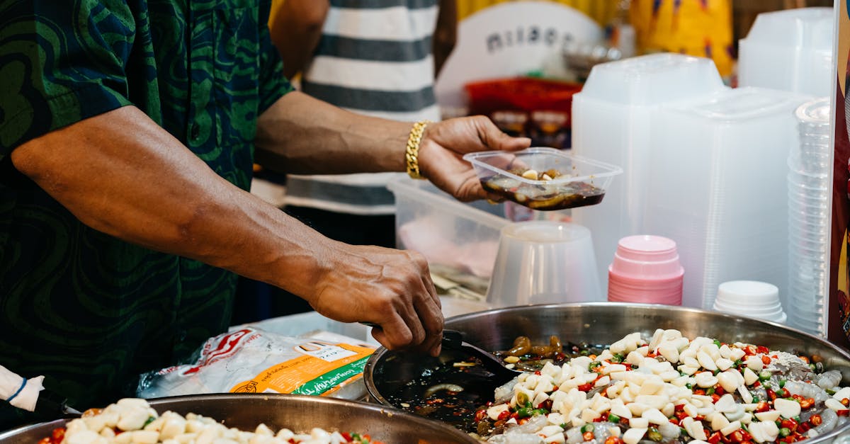 Close-up of a street food vendor serving a spicy dish with hands at a bustling market.