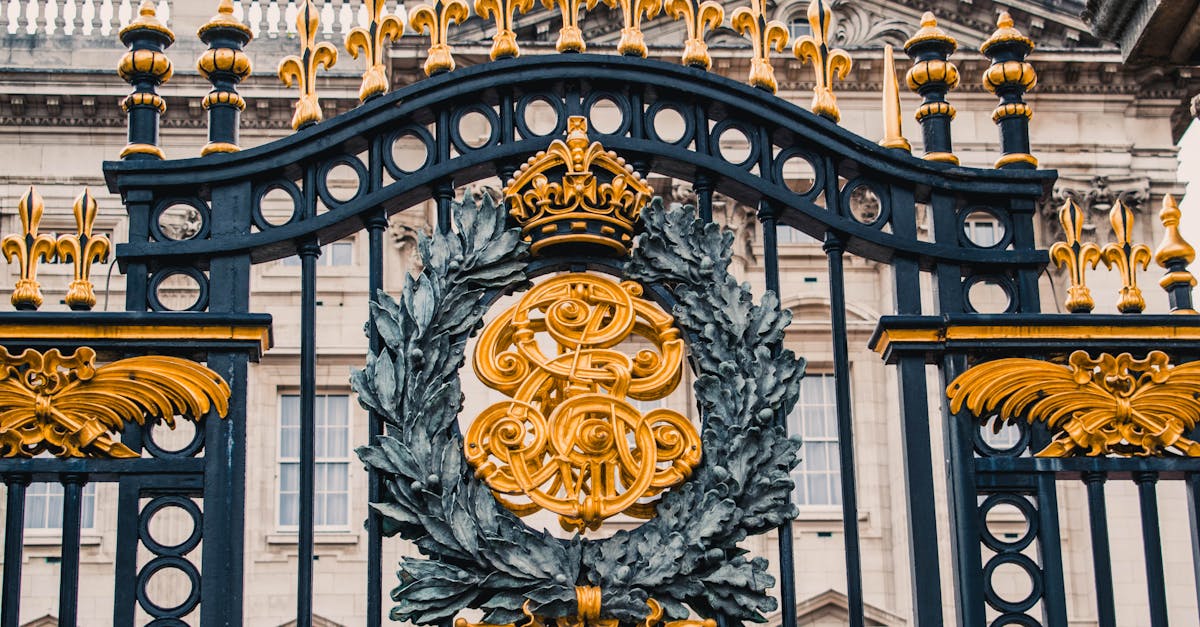 Detailed view of the ornate gold and black iron gate at Buckingham Palace, London.