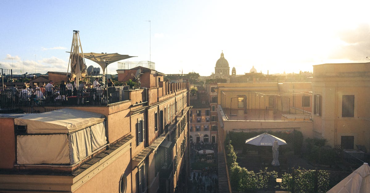 Rooftop restaurant with a view of a Roman skyline and sunset, showcasing urban architecture and vibrant life.