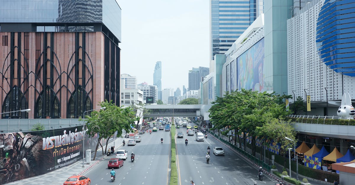 Vibrant city street in Bangkok featuring modern architecture, traffic, and urban greenery.