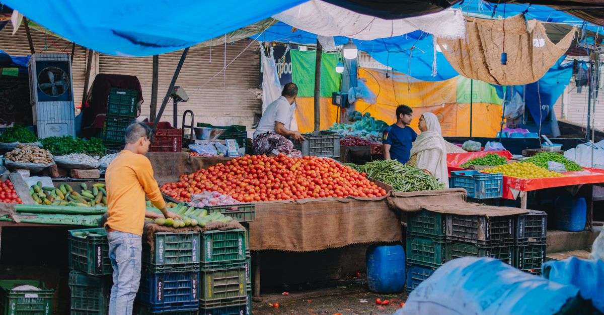 A lively outdoor market scene showcasing vendors selling fresh fruits and vegetables.