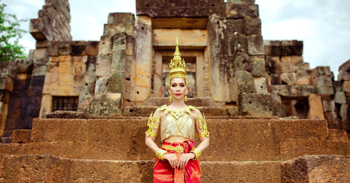 A woman in traditional Cambodian clothing poses at an ancient temple, showcasing cultural heritage.