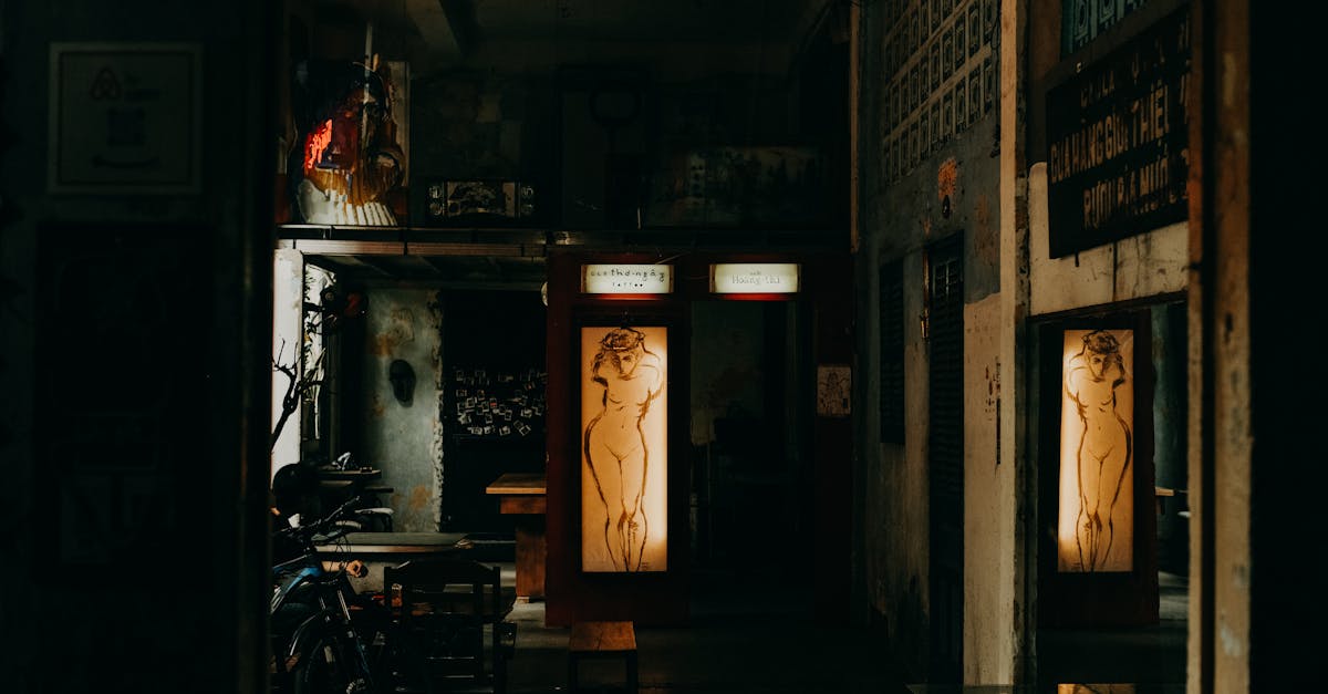 Dimly lit café interior featuring illuminated nude artwork and rustic charm.