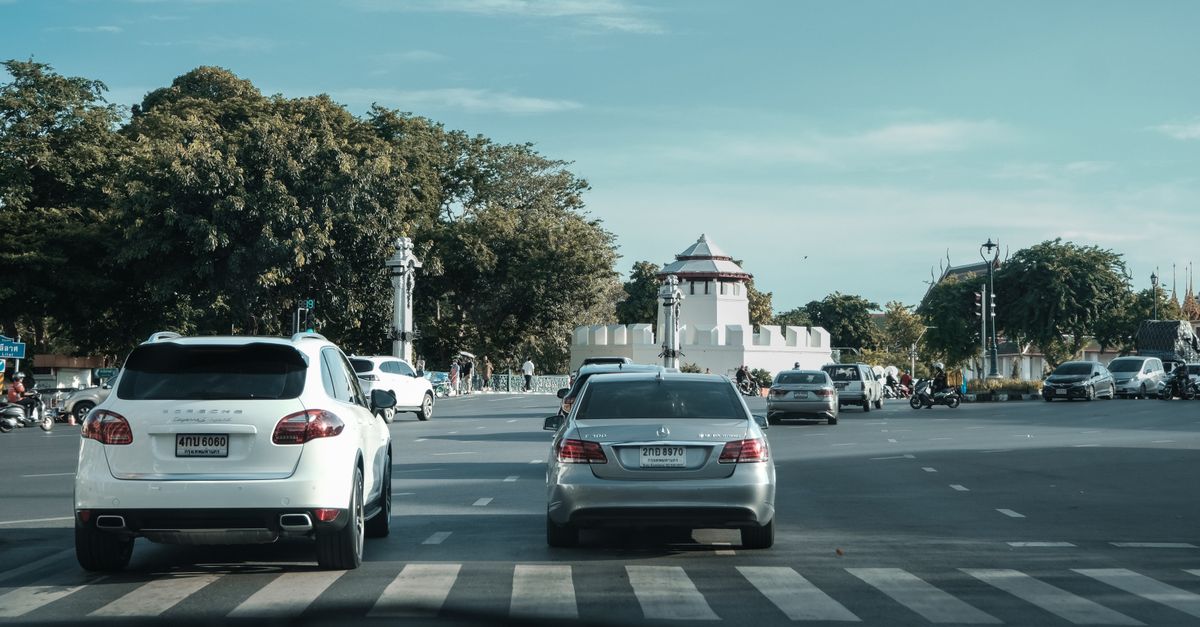 Cars driving on a city street near a historical landmark, under a clear blue sky.