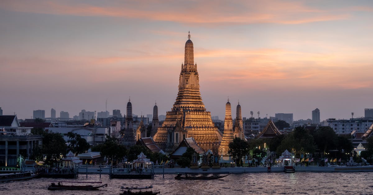Beautiful view of Wat Arun temple by the river in Bangkok during sunset.