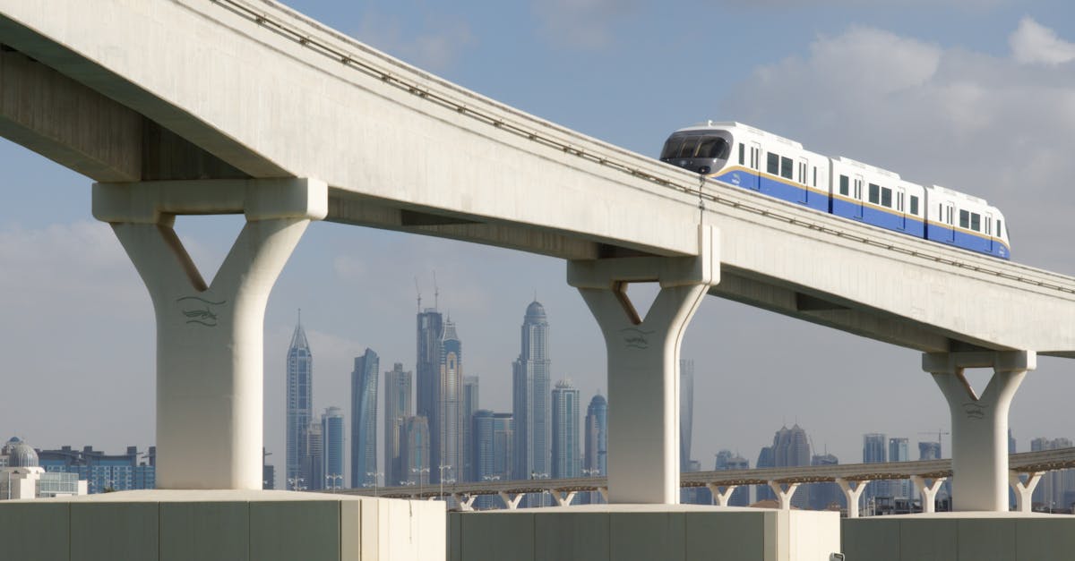 Monorail passing through modern overpass, Dubai skyline in the background, cloudy day.