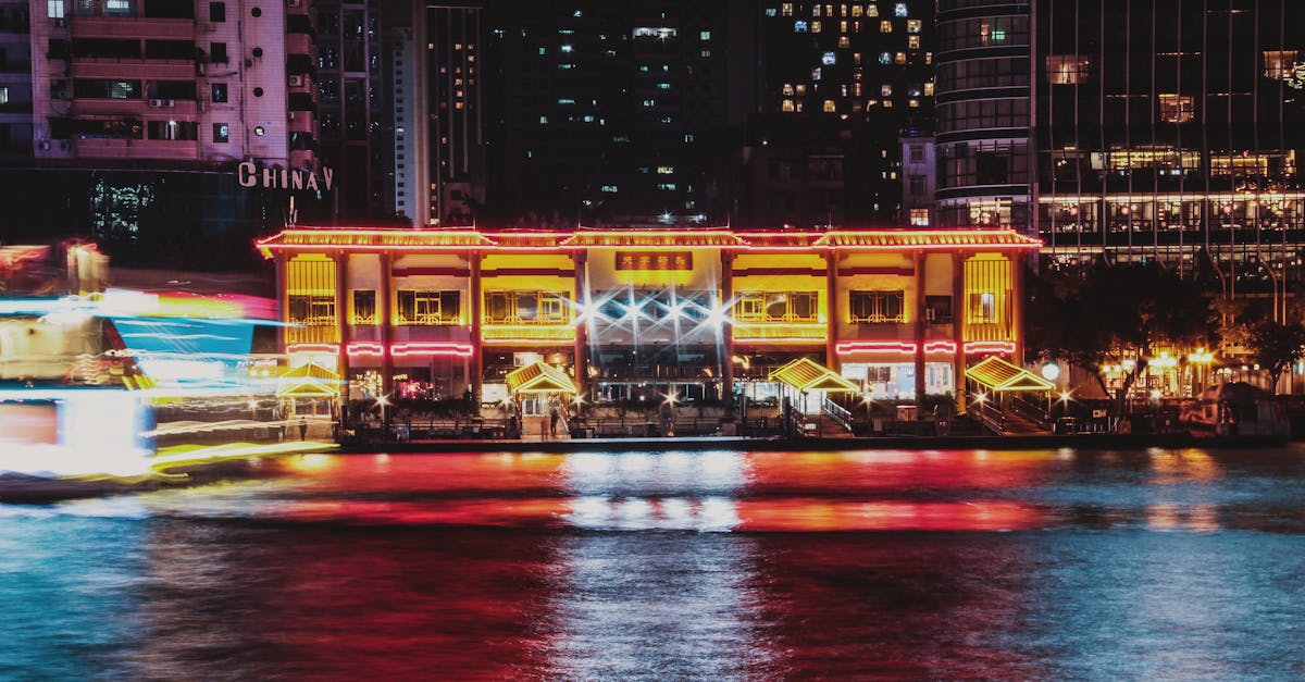 Illuminated riverside building in Guangzhou with colorful reflections at night.