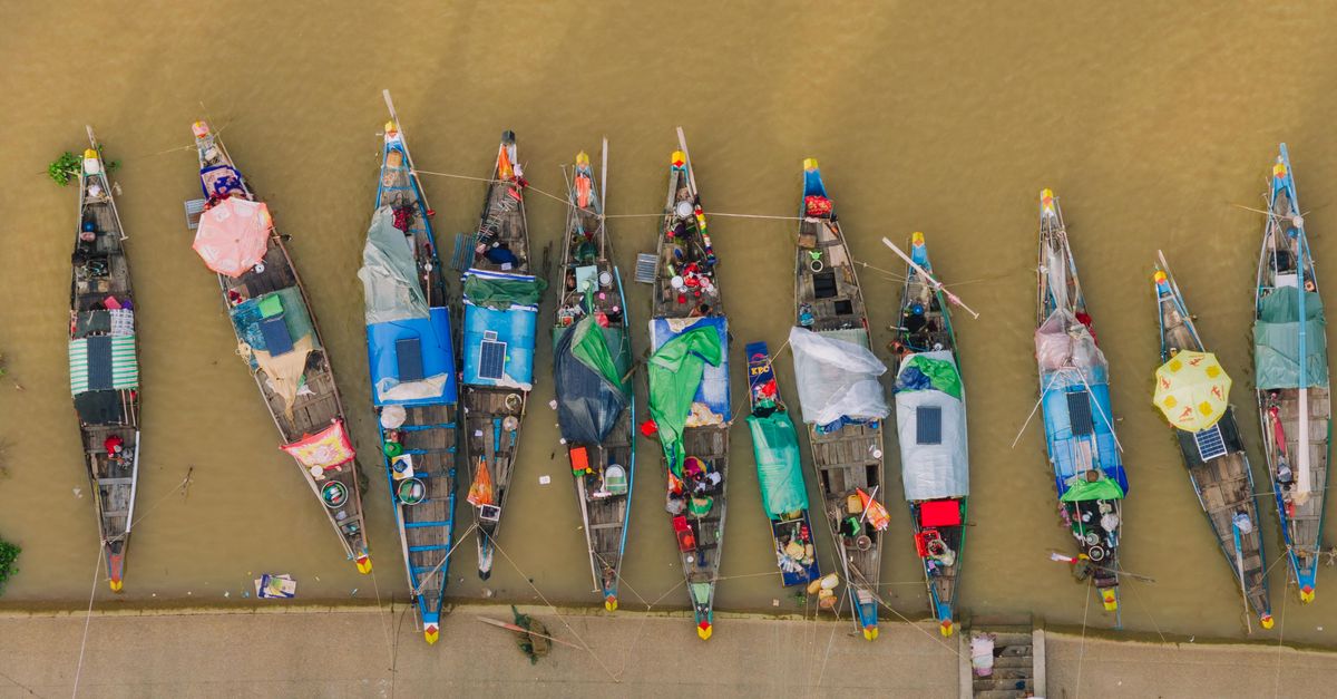 Colorful boats moored along the riverbank in Phnom Penh, Cambodia, viewed from above.