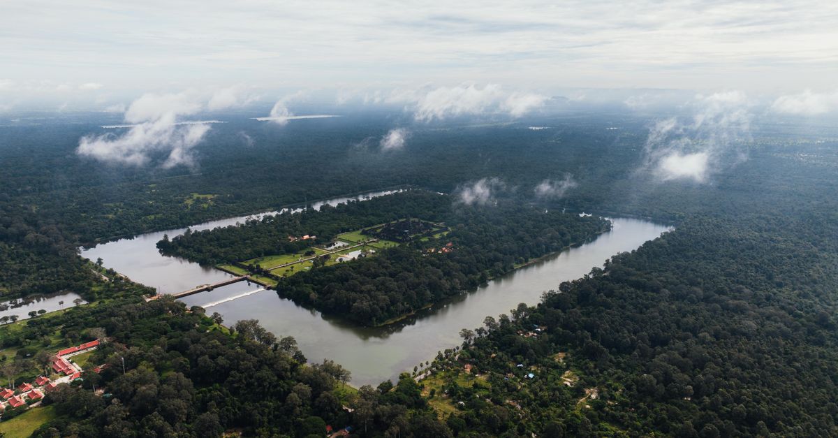 Stunning drone capture of Angkor Wat in Cambodia, enveloped in dense greenery and water.
