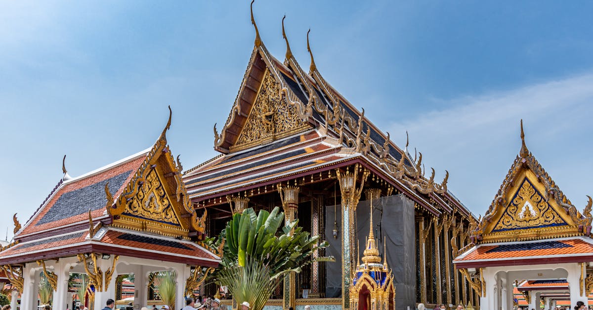 Explore the stunning Wat Phra Kaew temple with traditional Thai architecture and tourists enjoying the vibrant scene.