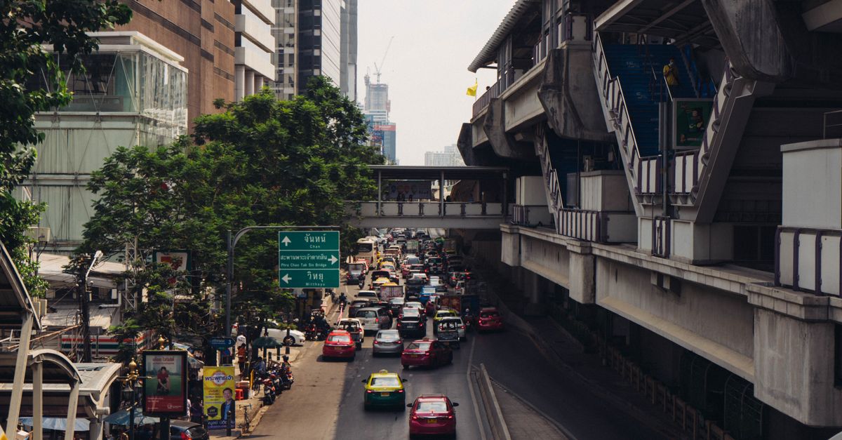 A bustling street in downtown Bangkok with traffic and modern architecture.