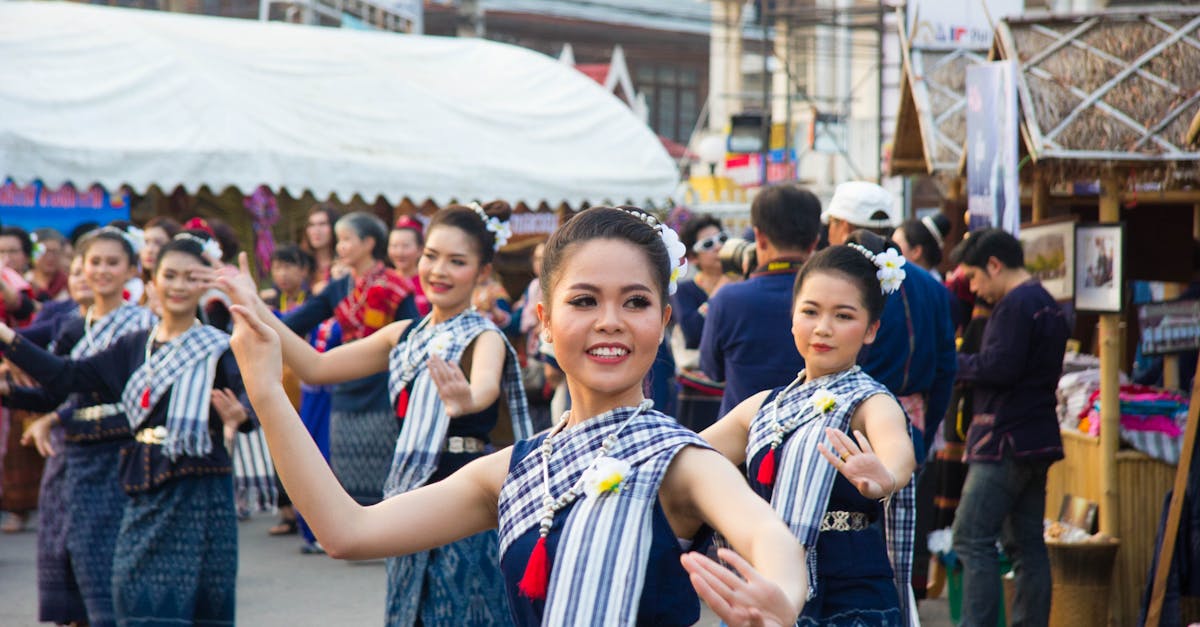 Group of Asian women in traditional costumes performing a cultural dance outdoors.