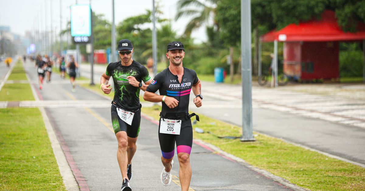 Two male athletes competing in a city marathon, running energetically on a pavement track.