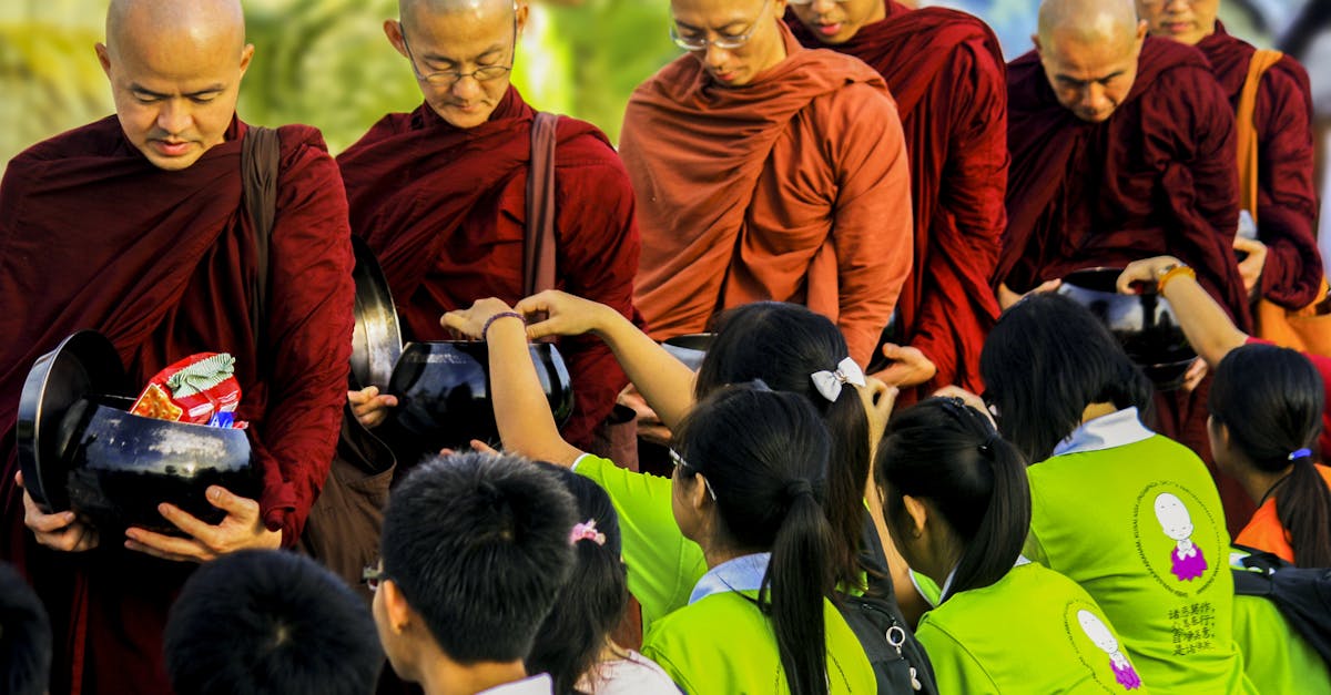 Buddhist monks in saffron robes receiving offerings from children in a peaceful ceremony.
