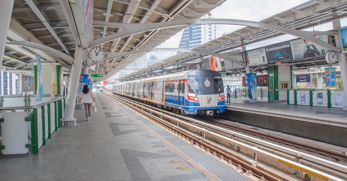 A bustling urban railway station with a modern train and commuters in daylight.